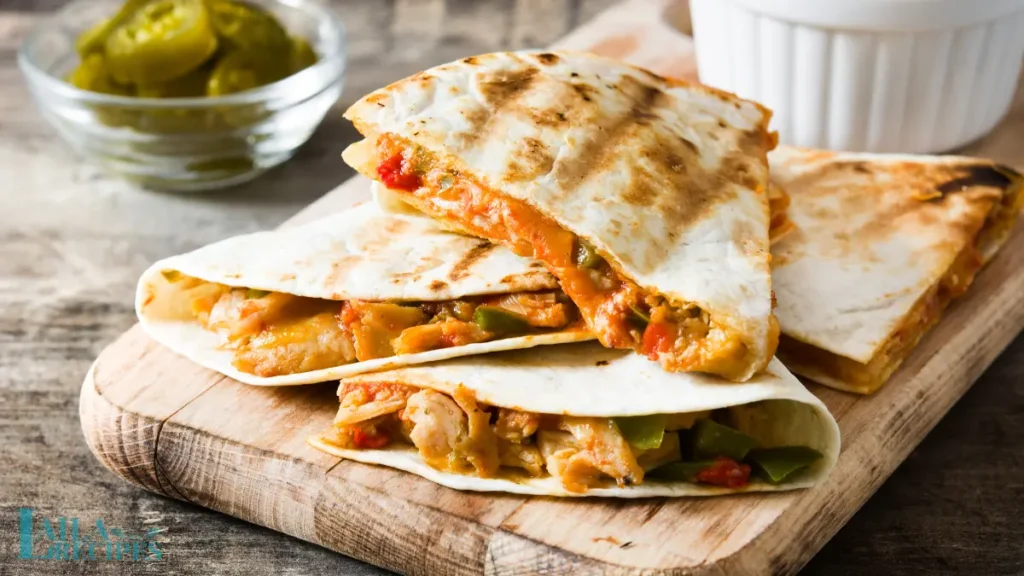 Cutting a quesadilla with a pizza cutter on a wooden board.