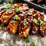 A plate of chicken teriyaki with sesame seeds and rice