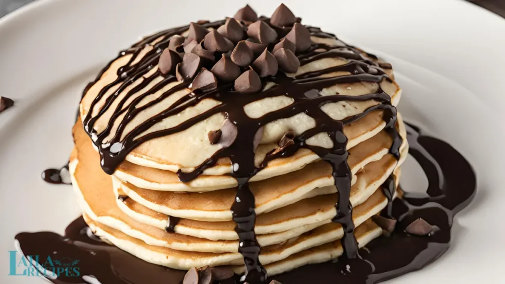 Stack of pancakes with maple syrup bottle beside.