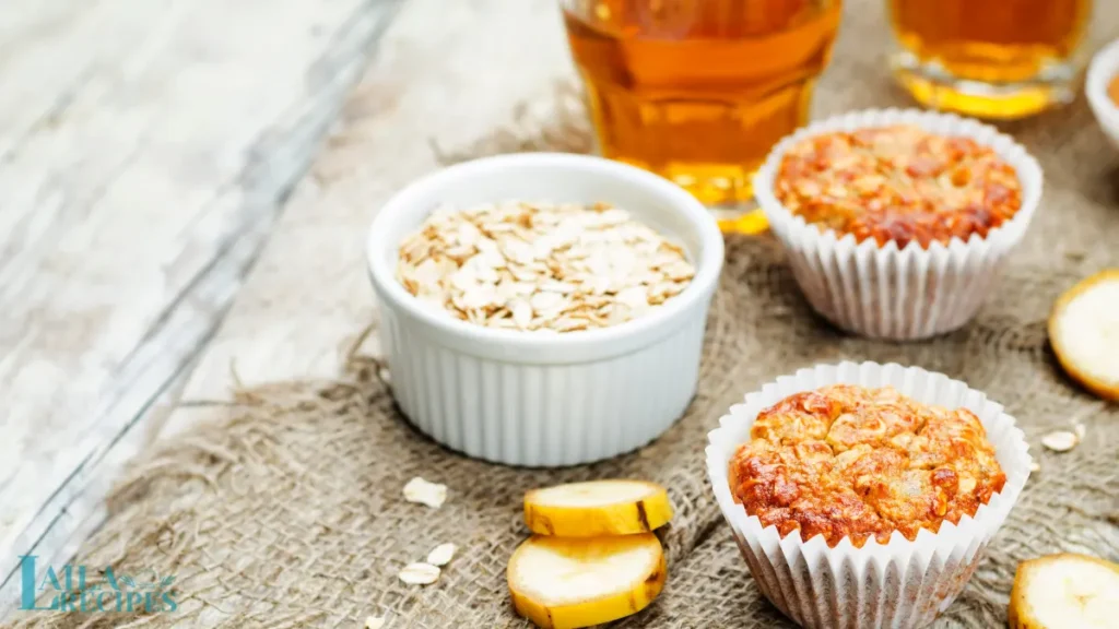 A stack of banana oat muffins on a wooden board with a cup of coffee.